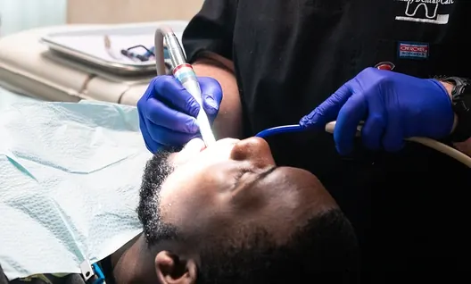 A dentist in the practice's black scrubs treating a patient.
