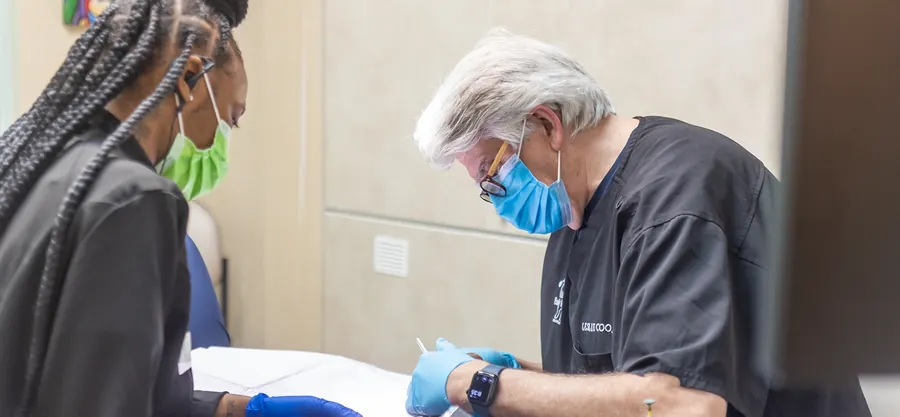 A dentist and an assistant treating a patient.