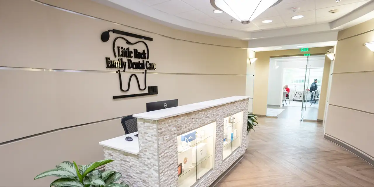 The reception desk at Little Rock Family Dental Care, with the practice's tooth-and-toothbrush sign on the wall behind it.