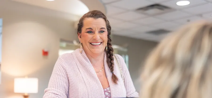 A patient smiling at the front desk as she checks in.